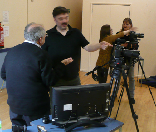 Jonathan discusses cameras with George in the tea break, while Roz demomonstrates features to Marije