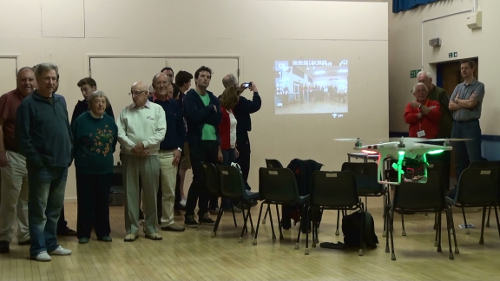 Members watching quadcopter as it filmed them & projected its image on the wall